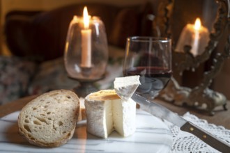 Chaource cheese presented sliced with bread and red wine in warm candlelight, typical of the