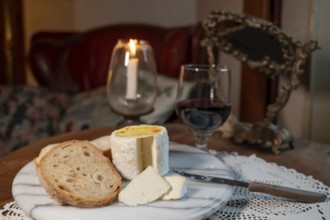 Chaource cheese presented sliced with bread and red wine in warm candlelight, typical of the