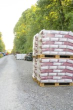 Pallets with building materials on a gravel road surrounded by forest, Hermann Hessebahn