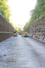 Construction site with heavy machinery on a stony road between steep embankments, Hermann Hessebahn