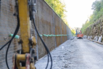 View along a construction wall with construction site vehicles and equipment, Hermann Hessebahn