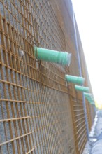 Side view of a construction wall with metal mesh and pipework, Hermann Hessebahn construction site,