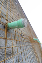 Close-up of a concrete wall with wire mesh and green pipes, Hermann Hessebahn construction site,