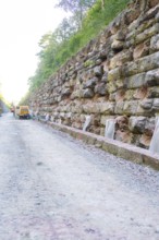 Robust stone walls along a gravel road in a wooded area, Hermann Hessebahn construction site, Calw,