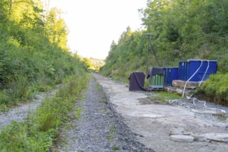 Gravel path with containers and cables in a wooded area along the track, Hermann Hessebahn