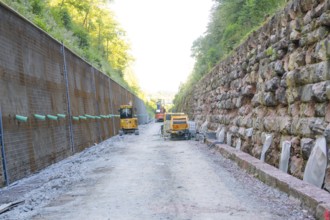 Abandoned construction site with equipment in a narrow street flanked by stone walls, Hermann