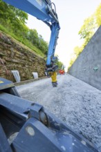 Close-up of crane arm on construction site, surrounded by concrete wall and trees, Hermann