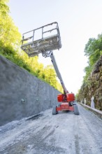 Lifting platform rises in front of concrete wall on construction site in the forest, Hermann
