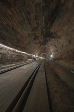 Dark tunnel with rails and lighting along the tunnel walls, construction of the Hermann Hesse
