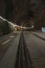 Long stone tunnel with lighting and construction equipment along the track, construction of the
