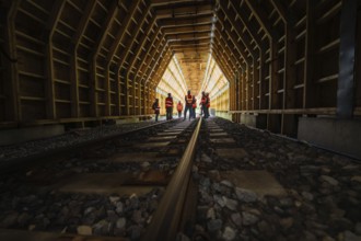 People in safety clothing standing in an illuminated wooden tunnel, construction of the Hermann