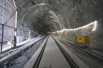 A tunnel still under construction with rails and artificial lighting, construction of the Hermann