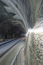 Unfinished tunnelling with exposed cables and rails in a shady environment, construction of the