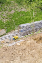 Construction site along the tracks on a hill, showing progress of the work and surrounding