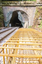 Construction site of a railway with tunnel and steel grid, surrounded by daylight and renovation
