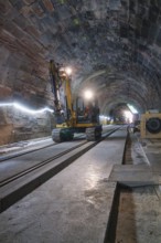An excavator in an illuminated tunnel on rails, with a depth of perspective in the scene,