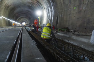 Construction workers in the tunnel working on the tracks. The scene is illuminated by strong light,