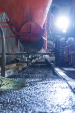 Concrete is poured from a construction vehicle in the tunnel. The area is brightly lit,