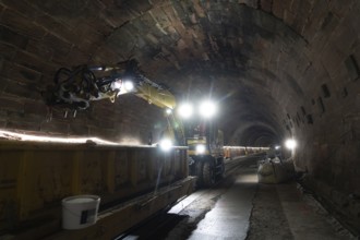 Tunnel lighting with track under construction and heavy machinery, construction of the Hermann