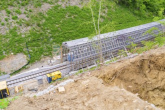 Aerial view shows railway tracks and construction work on a hill surrounded by vegetation,