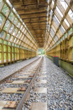 Empty wooden tunnel with view of green landscape through the transparent area, construction of the