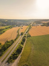 Wide landscape with road and fields at sunset, harmonious and natural surroundings, construction of