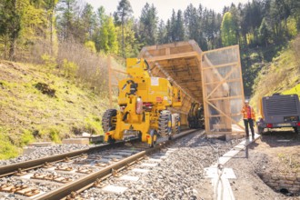 Yellow machine at the tunnel entrance with a worker next to it, construction of the Hermann Hesse