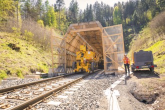 Machine and worker at the entrance to a tunnel in the forest, construction of the Hermann Hesse