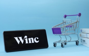 Dhaka, Bangladesh- 03 July 2025: Smartphone with Winc logo next to a small shopping cart and boxes