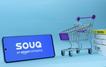 Dhaka, Bangladesh- 03 July 2025: Smartphone with Souq logo next to a small shopping cart and boxes