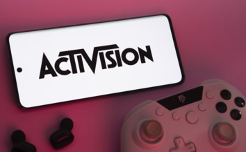 Dhaka, Bangladesh- 23 Sep 2025: Smartphone with Activision logo, game controller, and earbuds on a