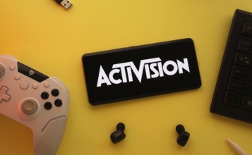 Dhaka, Bangladesh- 23 Sep 2025: Smartphone with Activision logo, game controller, and earbuds on a