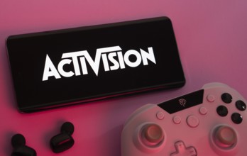 Dhaka, Bangladesh- 23 Sep 2025: Smartphone with Activision logo, game controller, and earbuds on a