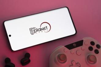 Dhaka, Bangladesh- 23 Sep 2025: Smartphone with 5th planet games logo, game controller, and earbuds