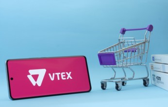 Dhaka, Bangladesh- 03 July 2025: Smartphone with VTEX logo next to a small shopping cart and boxes