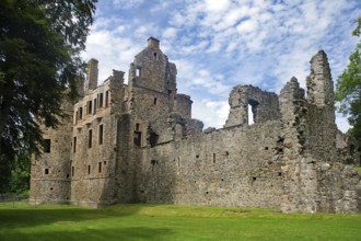 Old castle ruins with crumbling walls on a green meadow under a blue sky, Huntly Castle,