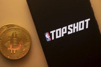 A Bitcoin and Top Shot logo on a black screen representing cryptocurrency
