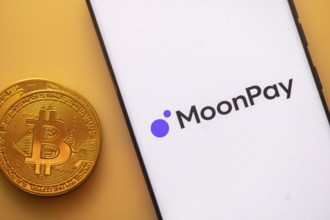 Bitcoin coin next to a smartphone displaying MoonPay logo on white screen