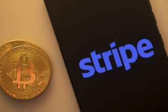 Bitcoin coin next to smartphone displaying the Stripe logo on a black background