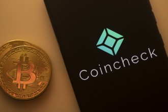 A Bitcoin coin next to a Coincheck logo on a black background