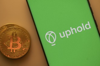 A Bitcoin coin next to an Uphold logo on a green background