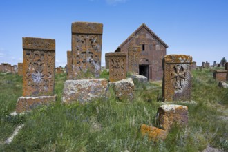 Old gravestones and a chapel in a green cemetery under a bright blue sky, cross stones, the world's
