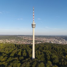 A tall television tower rises above a forest landscape under a clear blue sky, Stuttgart,