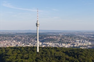 A tall television tower is surrounded by a green forest landscape under a clear sky, Stuttgart,