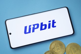 Dhaka, Bangladesh- 19 Sep 2025: Upbit logo on smartphone screen near Bitcoin coin and QR code on