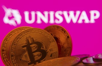 Dhaka, Bangladesh- 09 Sep 2025: Close-up of Bitcoin coins with the Uniswap logo visible on a screen