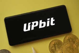 Dhaka, Bangladesh- 19 Sep 2025: Upbit logo on smartphone screen near Bitcoin coin and QR code on
