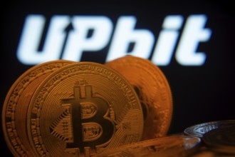 Dhaka, Bangladesh- 18 Sep 2025: Close-up of Bitcoin coins with thex Upbit logo visible on a screen
