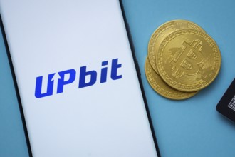 Dhaka, Bangladesh- 26 Aug 2025: Upbit logo on smartphone screen near Bitcoin coin and QR code on