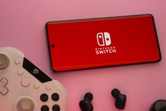 Dhaka, Bangladesh- 15 July 2025: Smartphone with nintendo switch logo, game controller, and earbuds